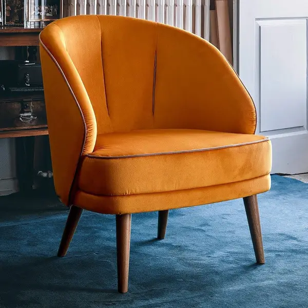 Angled view of the Alissa Lounge Chair, featuring orange velvet upholstery and a wooden frame. Comfortable, stylish seating.