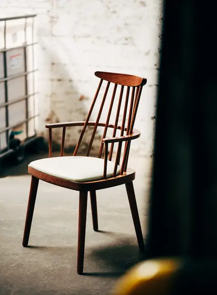 Bam Armchair with a solid wooden frame and a white upholstered seat, featuring a spindle back and four legs, angled view.