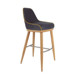 Upholstered Glow barstool with wood frame and metal footrest. The seat and back are dark gray with yellow piping and diamond stitching.