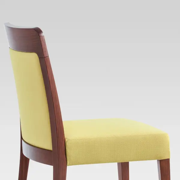 Profile view of a Dora Side Chair, showcasing a rich wooden frame paired with bright yellow upholstered seat and back.