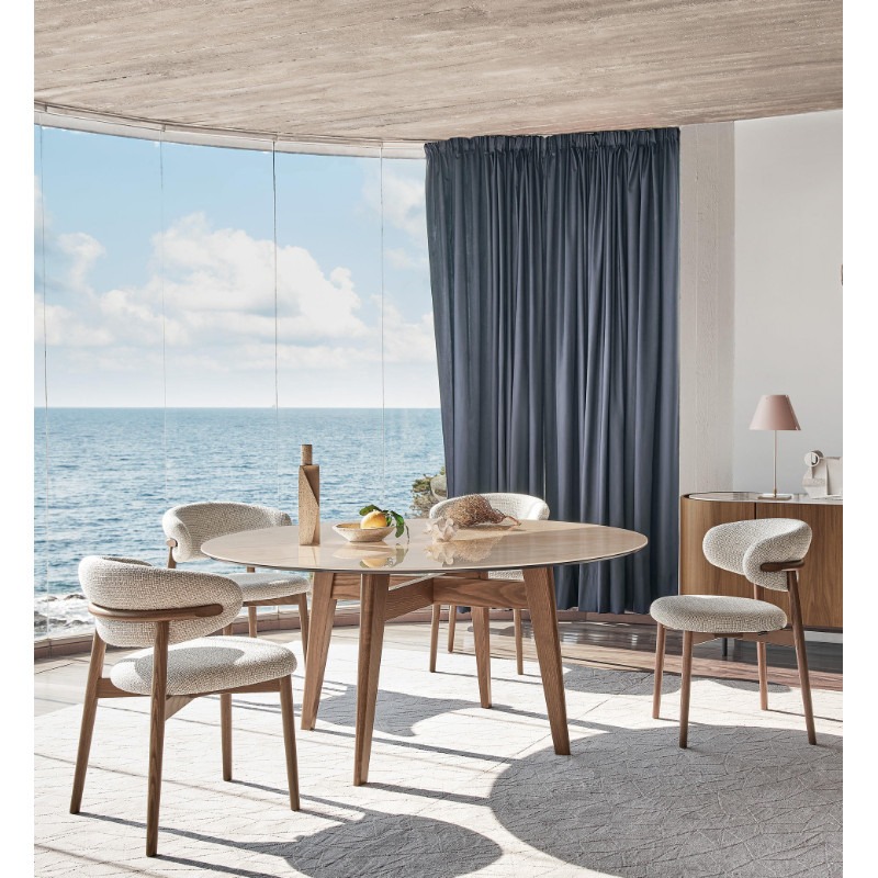 Oleandro side chair in a dining room setting. Upholstered seat and back with a wooden frame.