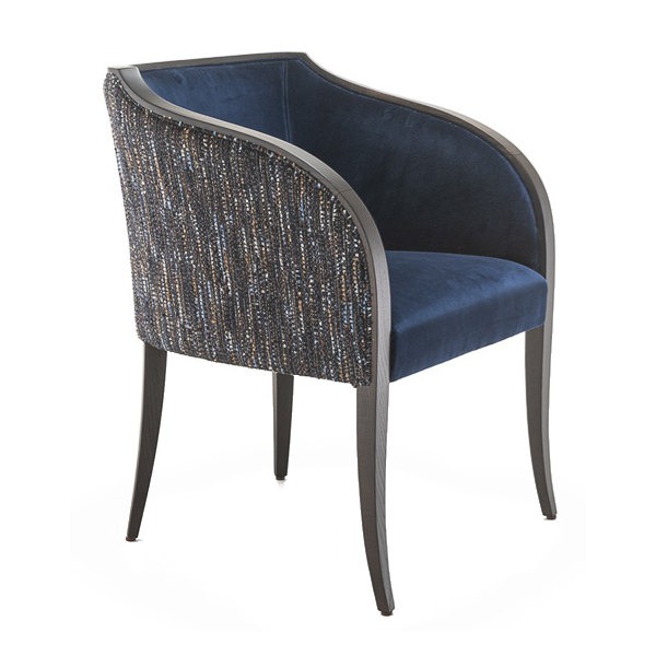 Angled view of the Serena armchair. Wooden frame, upholstered in blue velvet and patterned fabric.