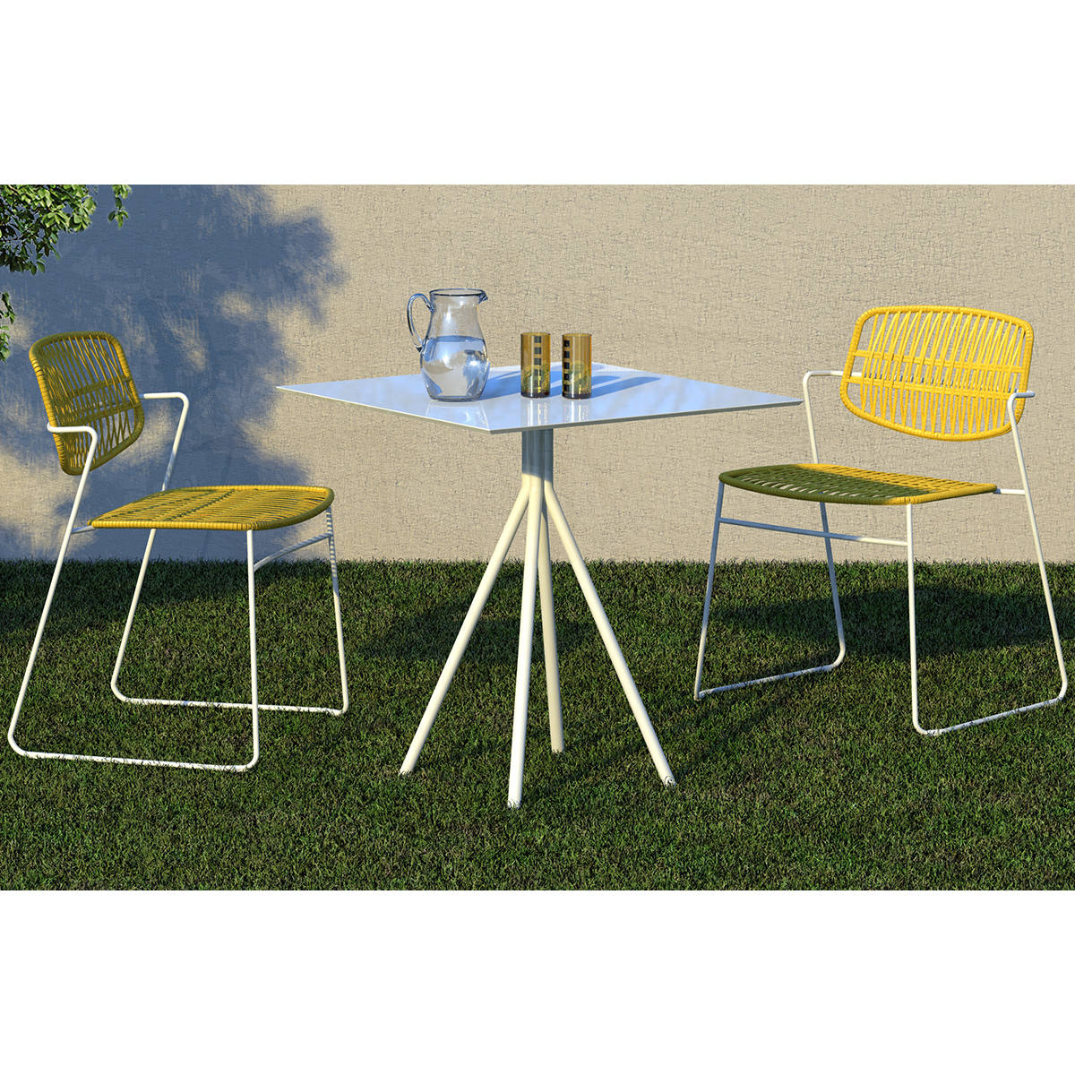 Two Serpentine armchairs with woven seats and backs, in yellow and green, paired with a white metal table on a lawn.