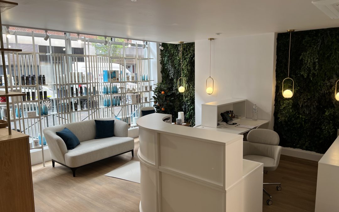 London Hair Clinic reception area. Modern design with product shelves, seating, and greenery.