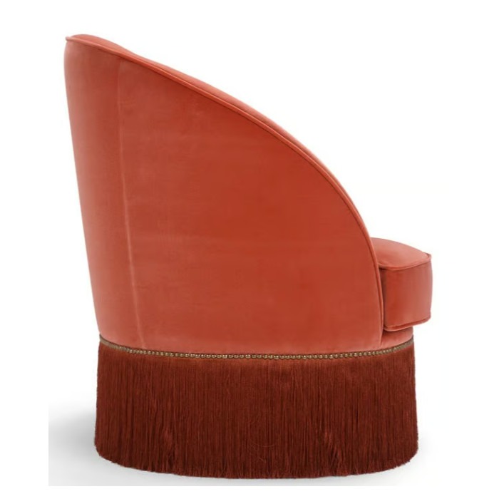 Side view of the Dione lounge chair. Upholstered in orange fabric with stylish, long fringe detail.