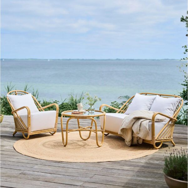 Outdoor setting with a Charlotte lounge chair and loveseat in rattan with white cushions.