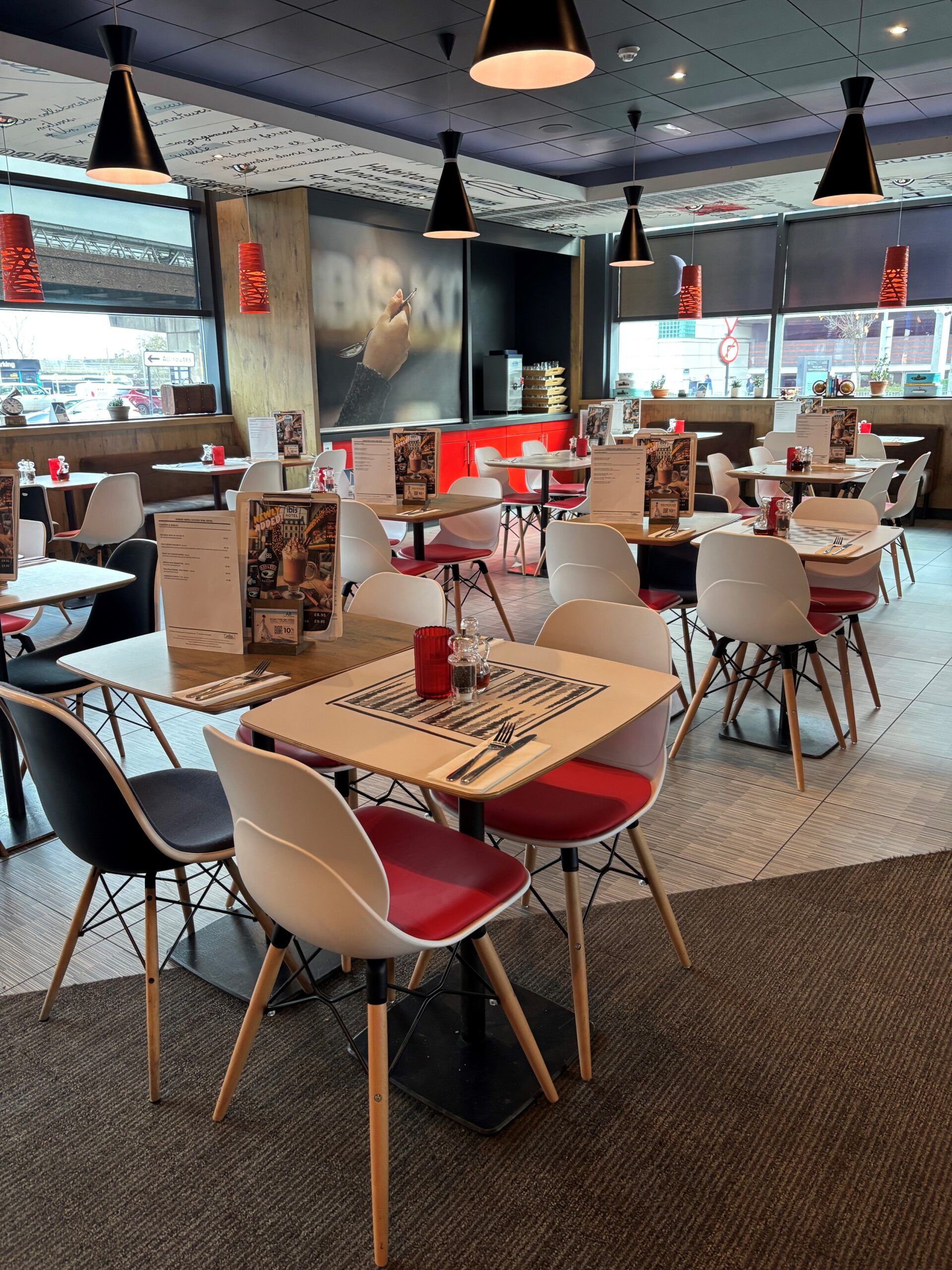 Ibis Hotel Birmingham restaurant interior. Tables and chairs are set for dining. Modern lighting.
