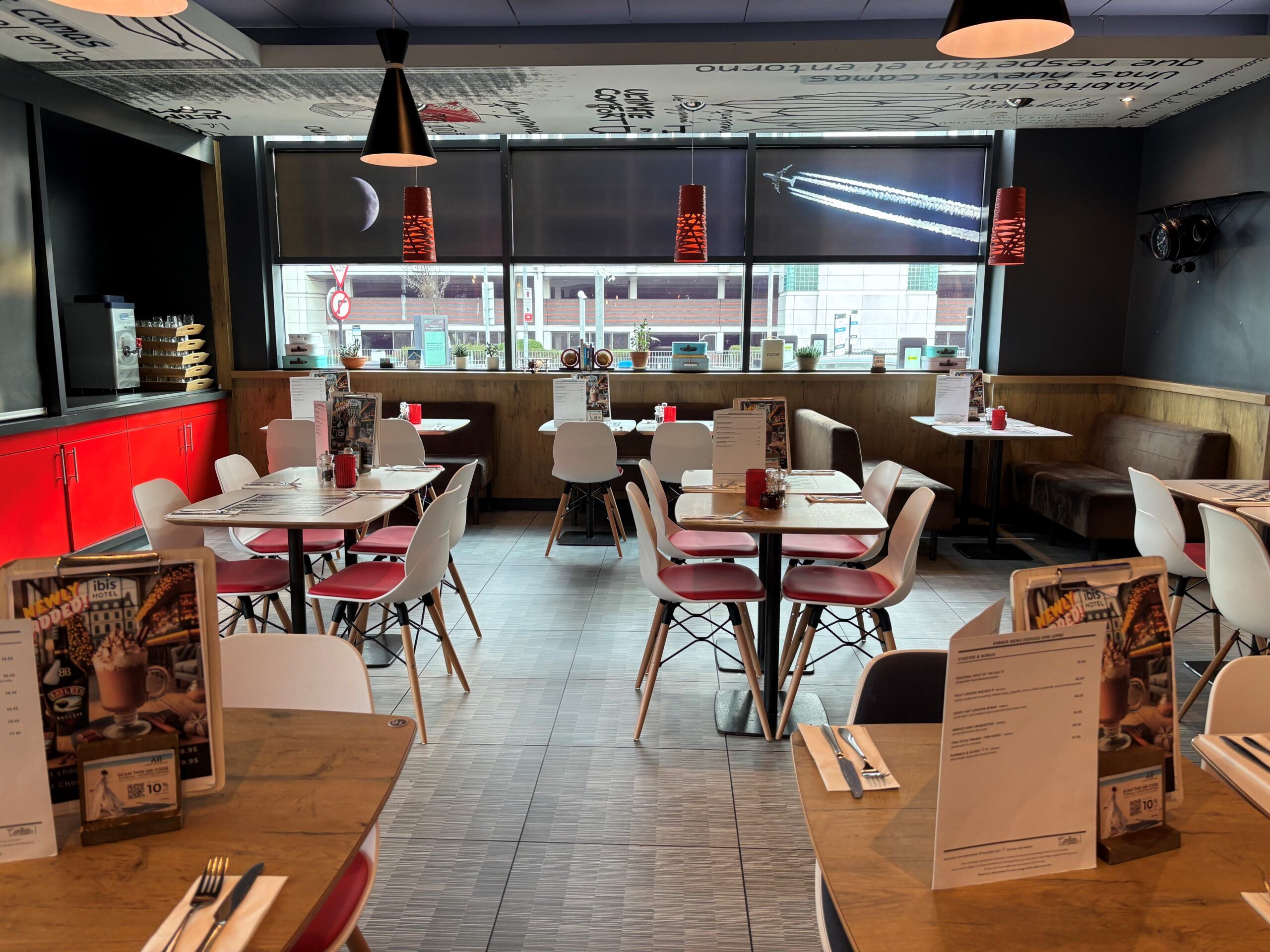 Ibis Hotel Birmingham restaurant interior. Tables with red chairs, natural light, modern design.