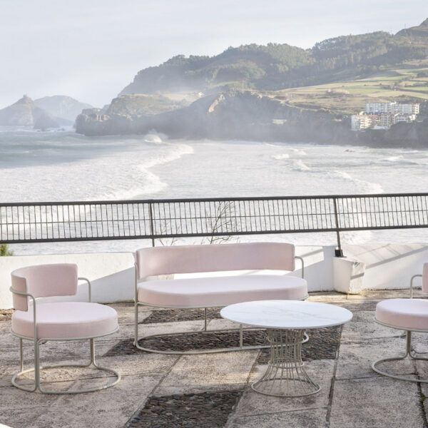 Outdoor seating set with Paradiso lounge chair, loveseat, and table. Upholstered in pink fabric with metal frames. Ocean view.