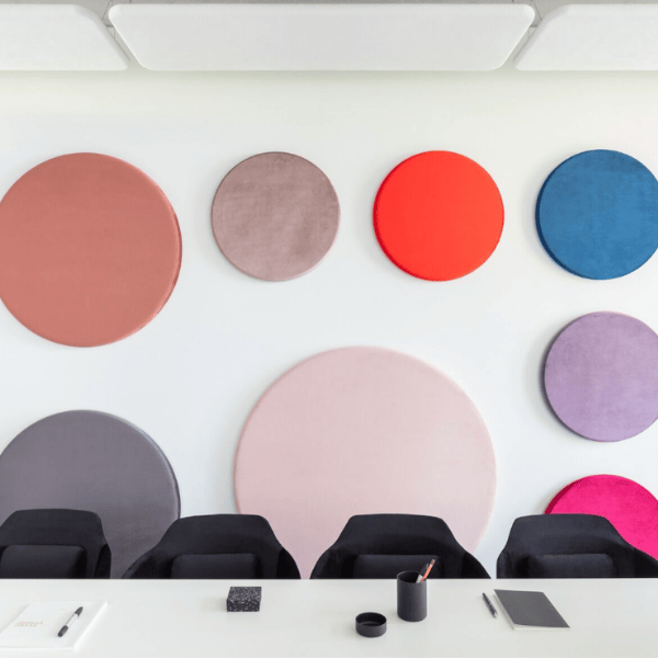 Misty Wall Acoustic: Colorful round soundproofing panels in various sizes and hues mounted on a white wall above a meeting table.
