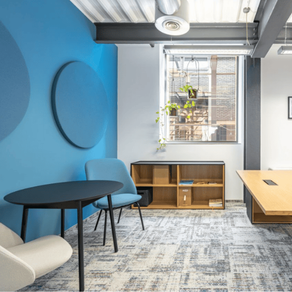 Misty Wall Acoustic panel in a blue office setting. The round, sound-absorbing panel is mounted on a blue wall.