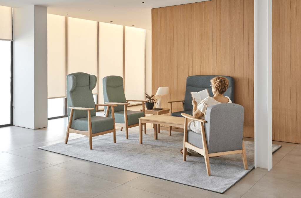 Health care furniture: Woman reading in a modern waiting room with chairs and a table.