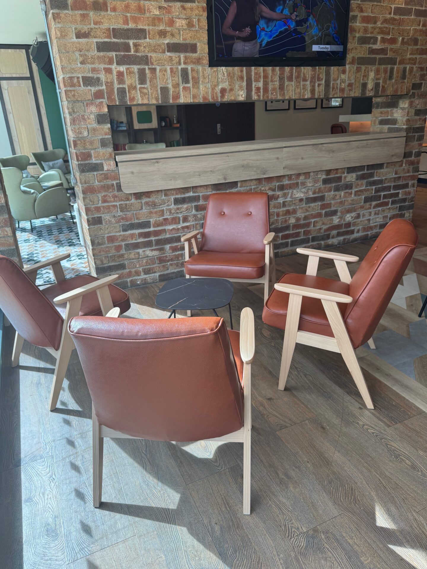 B&B Hotel Warrington B&B Hotel Warrington seating area with modern brown leather chairs on wood floors, brick wall accent.