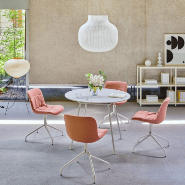 Angled view showcasing four Baltic Soft M side chairs in a light peach fabric, complemented by white metal frames around a round table.