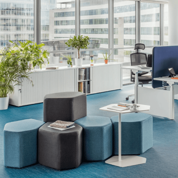 Angled view of Bazalto Pouf seating arrangement, showcasing blue and gray upholstered poufs in a modern office space.