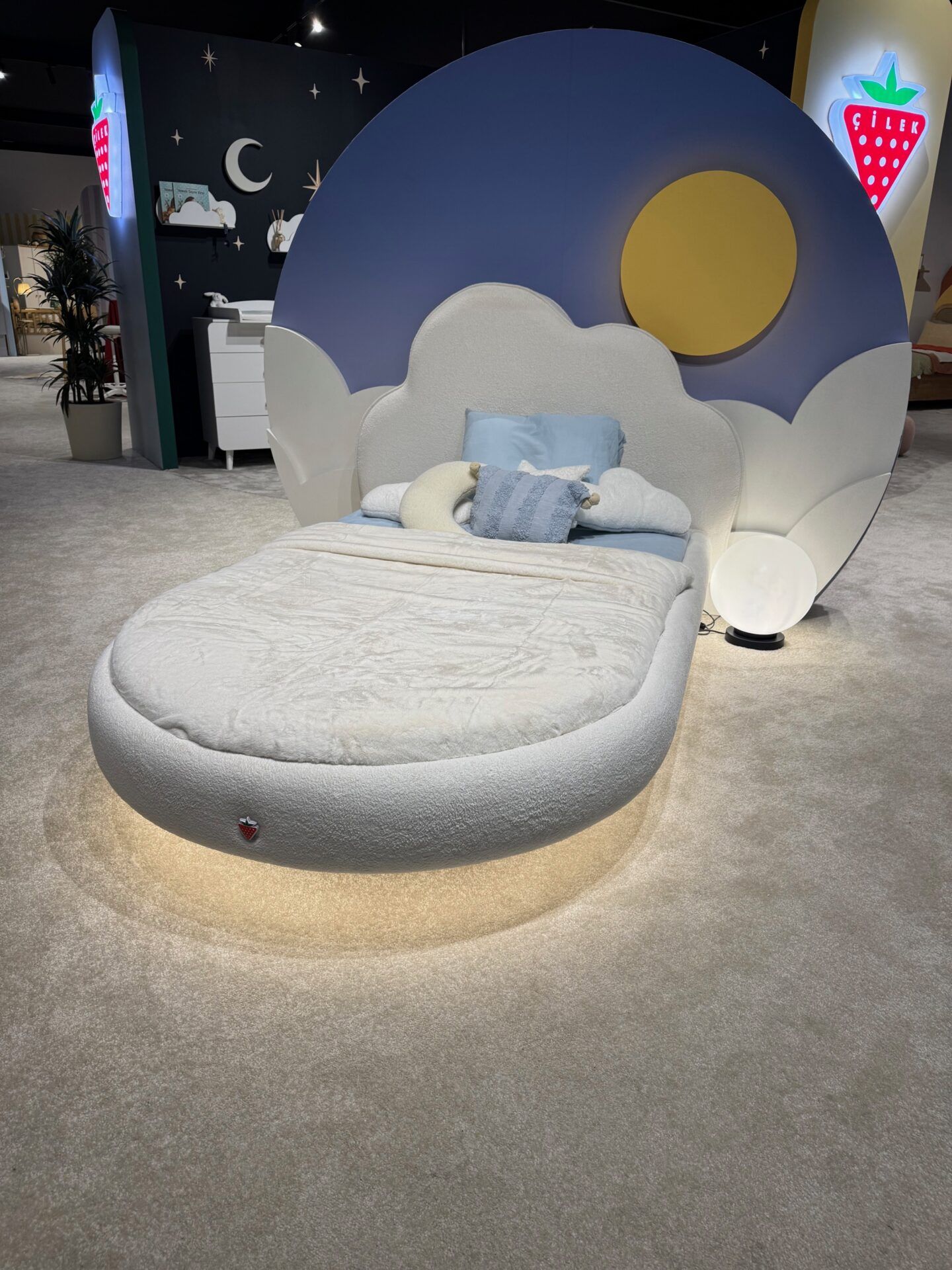 Istanbul Furniture Fair: Unique bed design with blue sky headboard and cloud-shaped frame, showcasing innovative furniture trends.