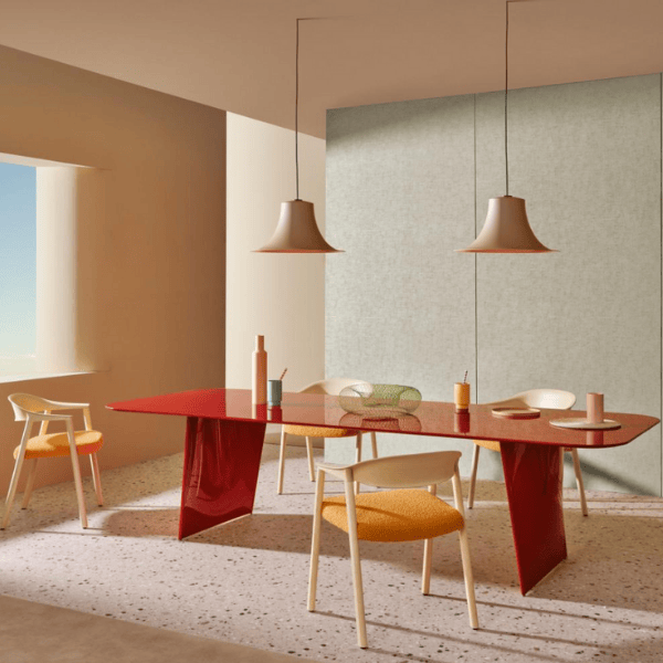 L004CW Pendant Light in a dining room setting. Features a flared metallic lampshade in a neutral color, suspended above a red table.
