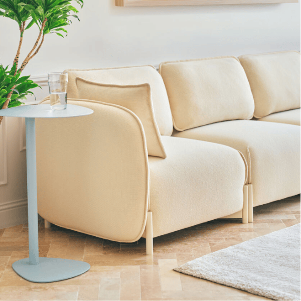 Angled view of the Linka Lounge Chair in cream upholstery with a metal frame, showcasing its soft, rounded design.