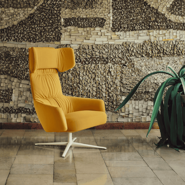Toro armchair in situ 3 Angled view of a yellow upholstered Toro Lounge Chair with a white metal base. Contemporary lounge chair for commercial use.