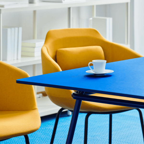 Angled view of the upholstered Ultra Armchair, featuring a mustard color, wooden frame, and modern design on a blue surface.