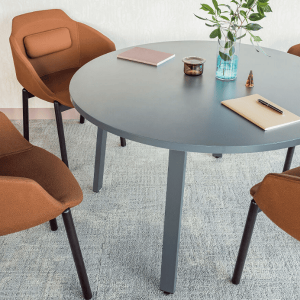 Angled view of Ultra Armchairs in tan fabric around a gray round table, ideal for office lounge, hospitality, or breakout spaces.