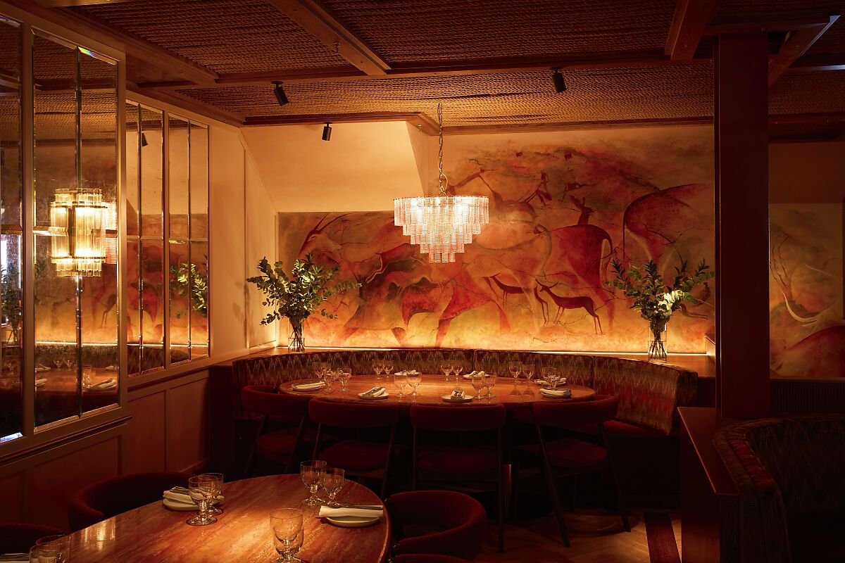 kudu restaurant Kudu Marylebone restaurant interior with a unique mural, chandelier, and set tables ready for diners.
