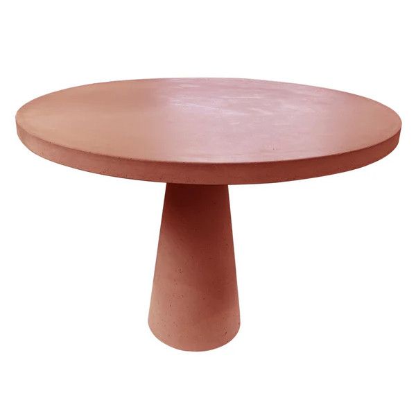 Close-up of a round Concrete Dining Table in a terracotta hue with a simple, modern pedestal base, outdoor contract furniture.