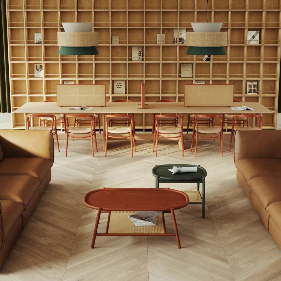 Angled view of a Drum Oval Coffee Table with a wood frame and top, in a modern office setting with sofas and a long table.