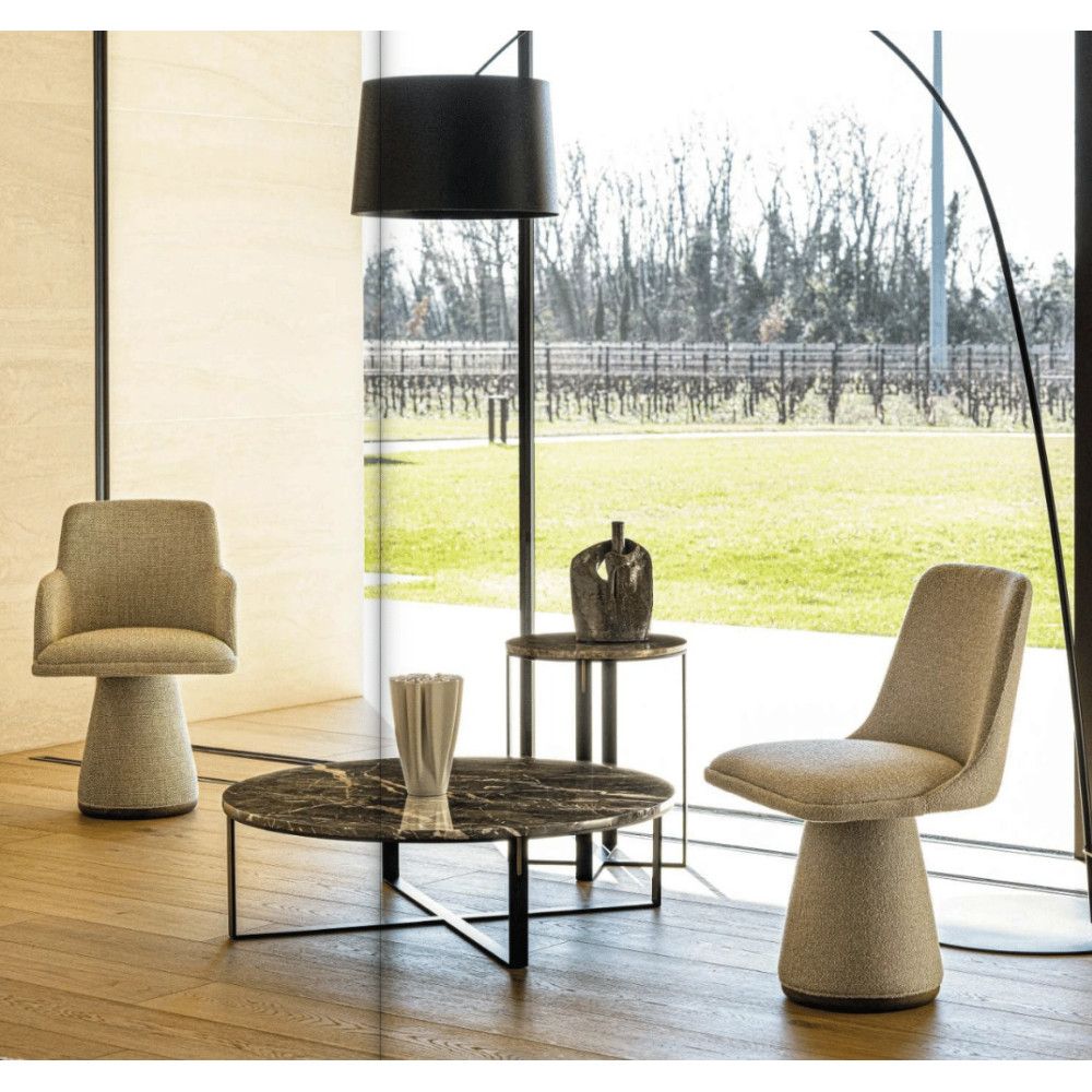 Angled view of two Flo Side Chairs with pedestal bases and neutral upholstery, plus coffee tables, in a modern interior setting.