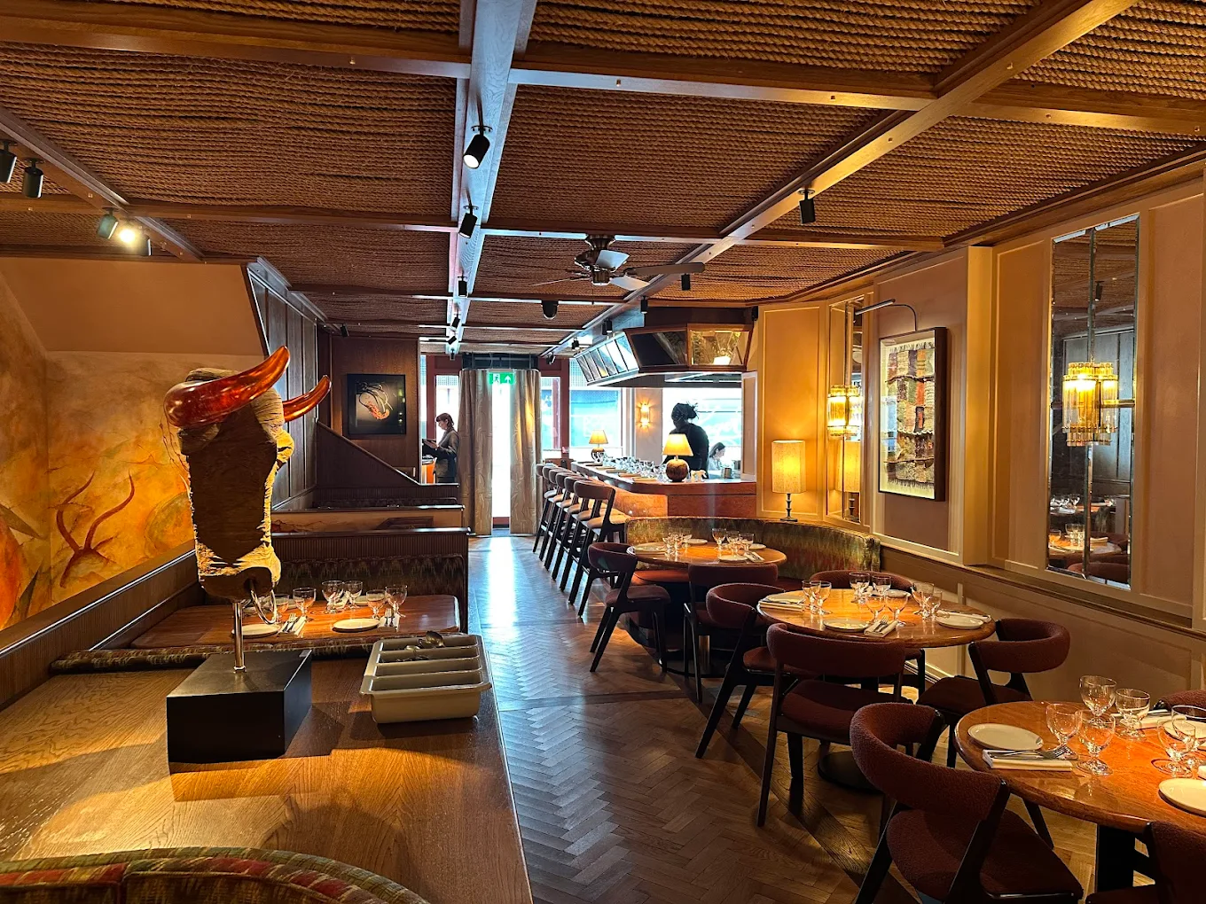 kudu restaurant Kudu Marylebone restaurant interior. Tables with chairs, bar, and a decorative sculpture with orange horns.