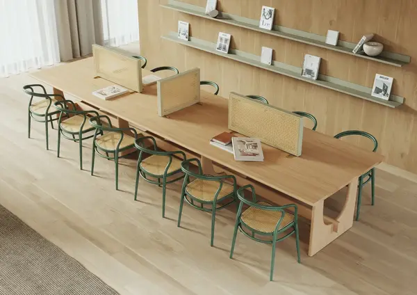 Angled view of a light wood Sund Conference Table with green chairs in a bright, modern office setting with books on shelves.