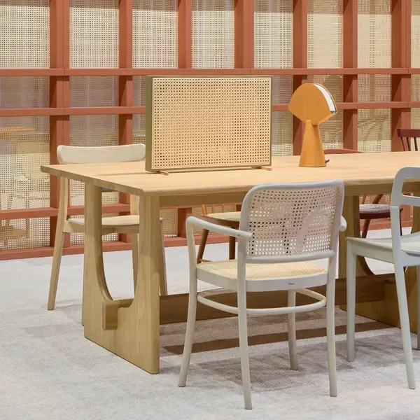 Stylish Sund Dining Table with a light wood finish and unique leg design, complemented by modern chairs and a warm lamp.