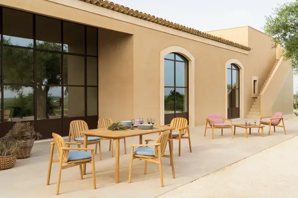 Twins Armchair in an outdoor setting. Features a wooden slat seat and back, with light blue cushions and a metal frame.