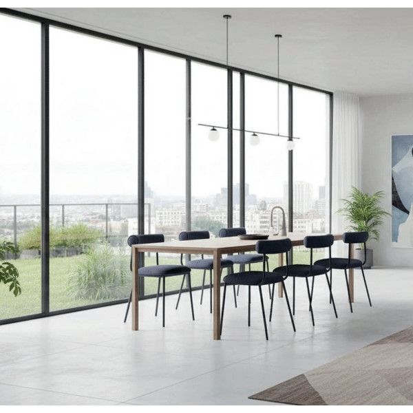 Modern dining room featuring Baya Side Chairs in blue upholstery with black metal frames around a wooden table, with large windows.