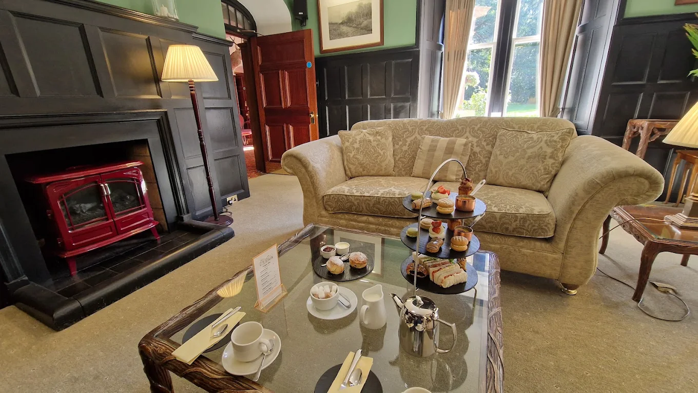 Hotel lounge area displays a patterned sofa and a glass table set with a tiered tray of pastries and tea service, Hotel Furniture.