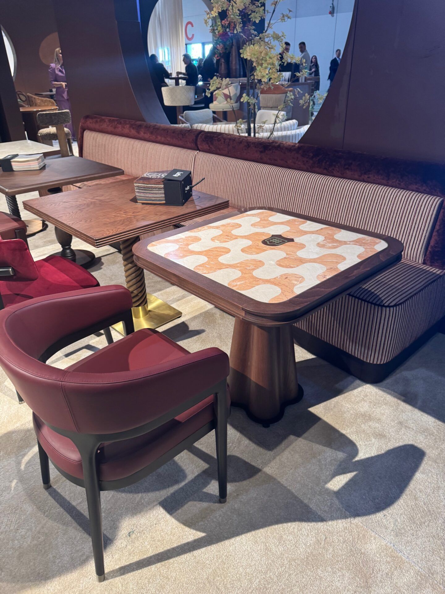 Salone del Mobile 2026 hospitality trends: Stylish restaurant booth seating with patterned table and modern red chairs.