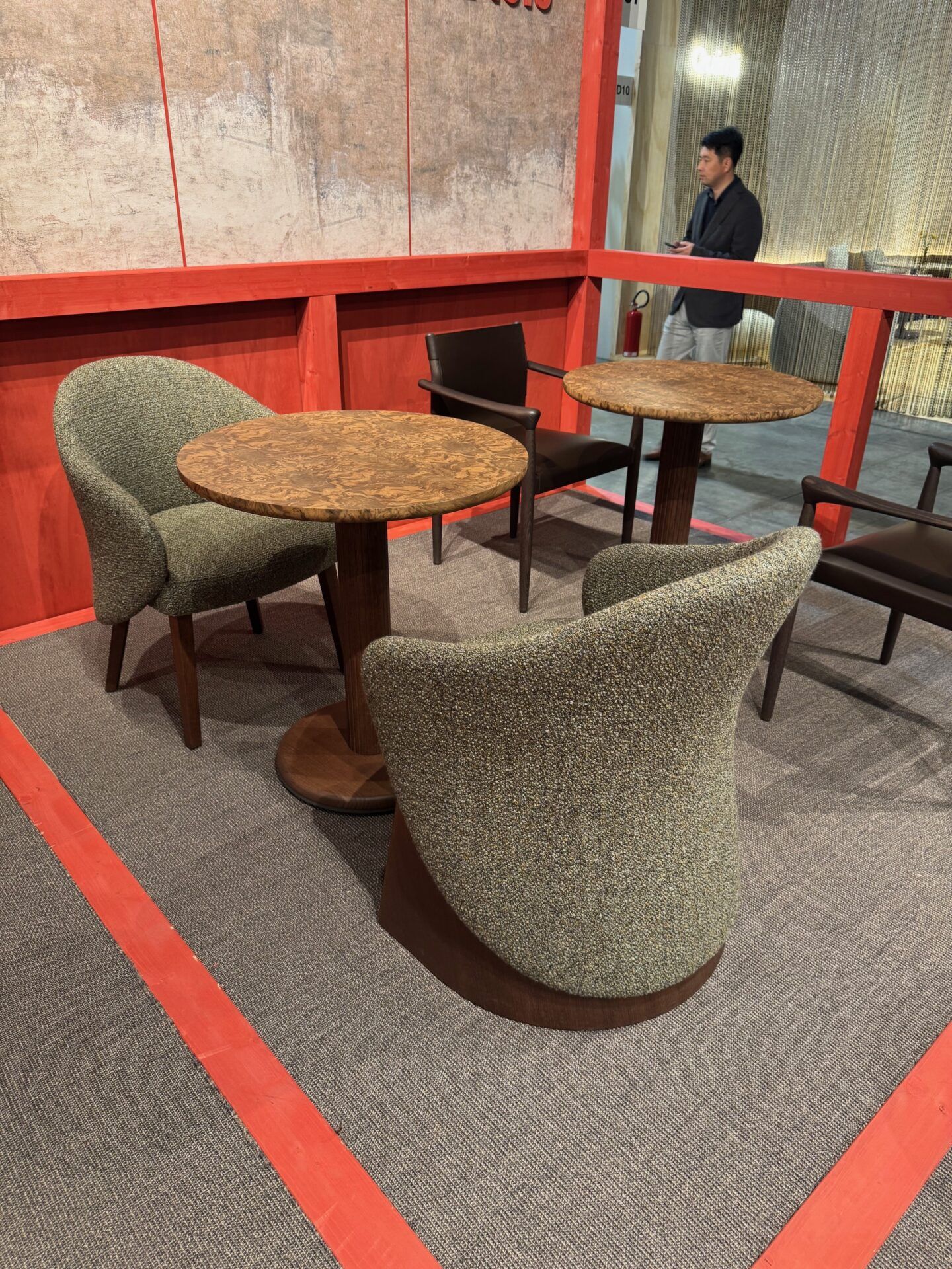 Salone del Mobile 2026 hospitality trend: Modern lounge with textured chairs and round wood tables. Furniture design for hotels.