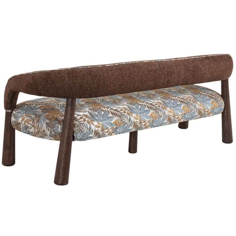 Rear-facing view of the Flow Sofa, showcasing its curved brown backrest and botanical seat cushion on sleek wooden legs.