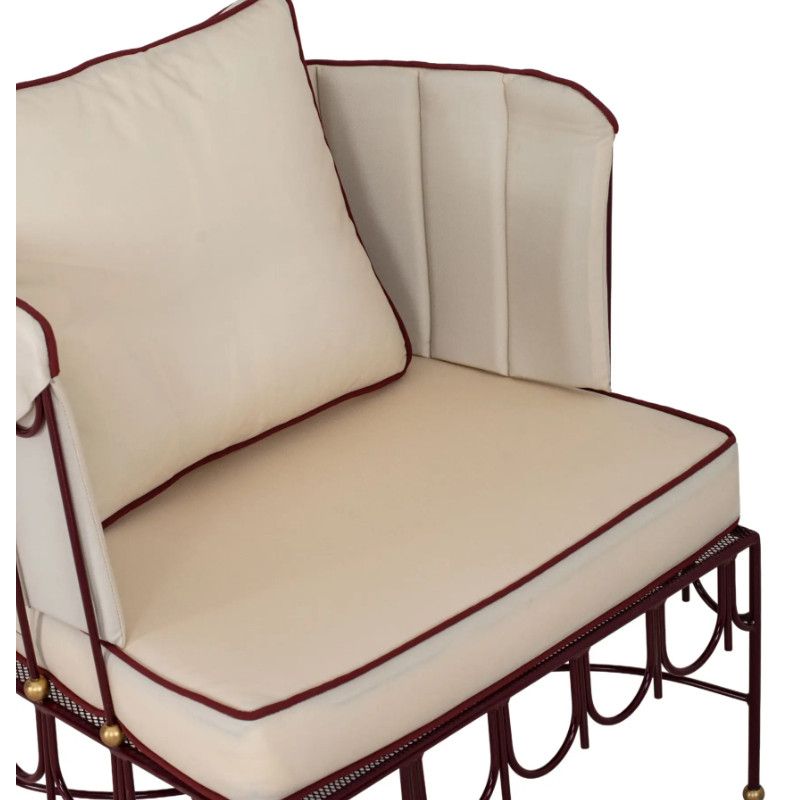 Close-up of Halycon Lounge Chair showing cream cushions, red piping, and a decorative maroon metal architectural base.