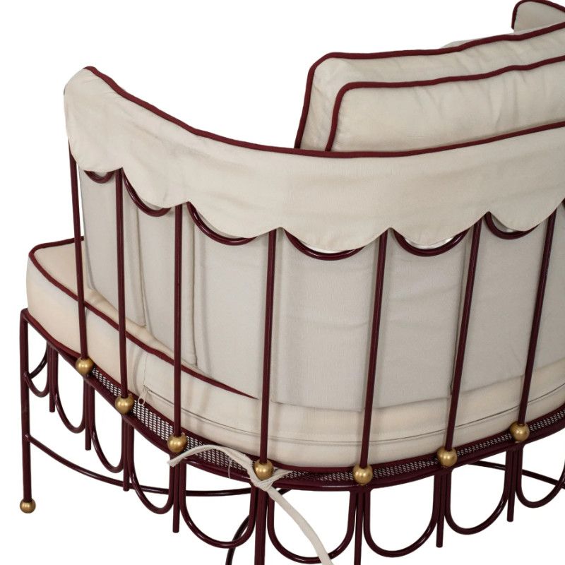 Rear angle of Halycon Lounge Chair showing intricate maroon metal frame details, gold accents, and cream cushions.