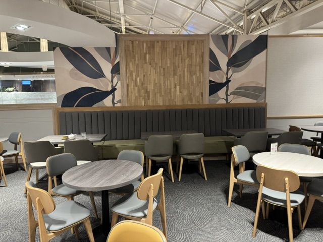 Haskins Garden Centre 9 Long grey banquette seating backed by wooden panels and botanical wall murals in a contemporary cafe area.