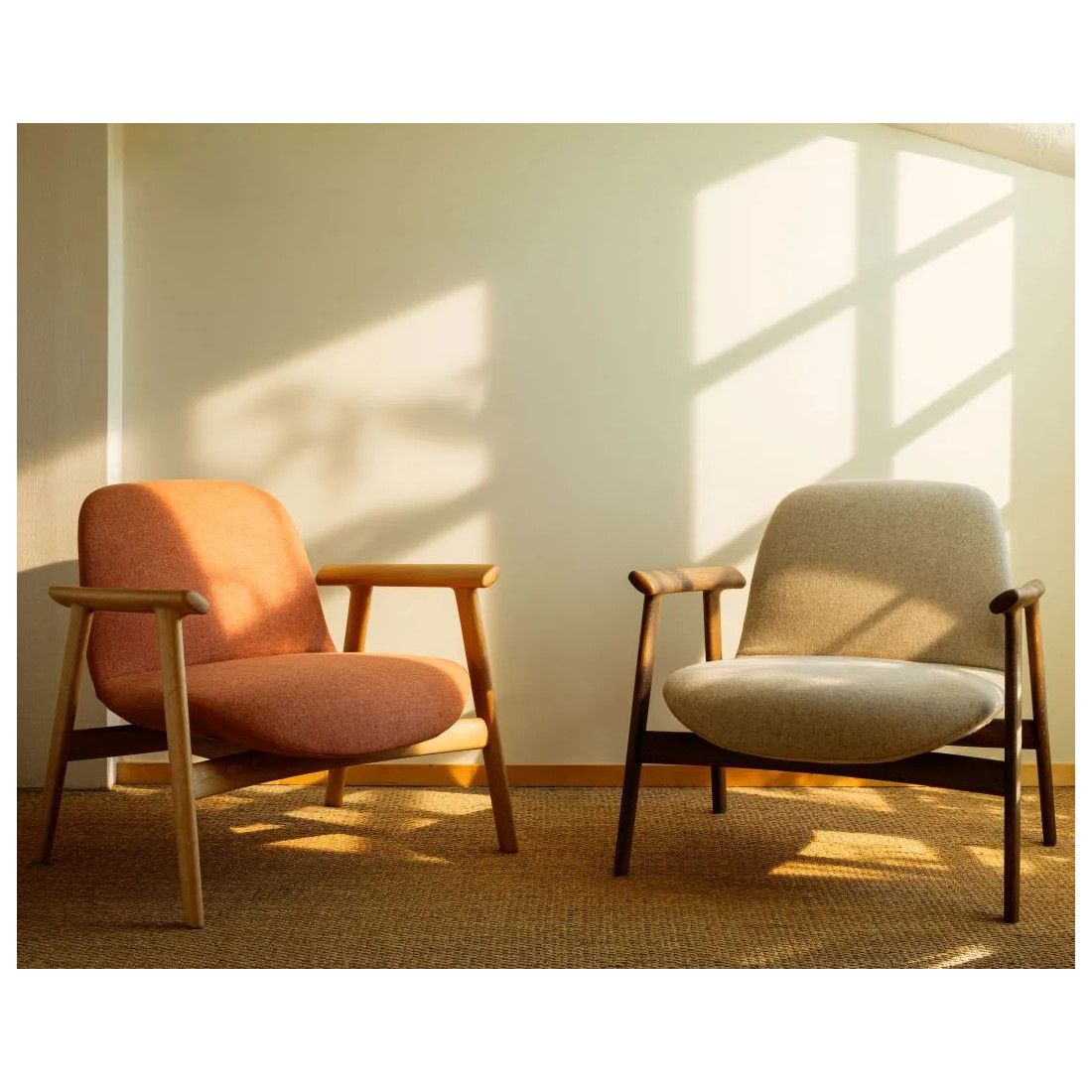 Two Ekuru lounge chairs side-by-side, one in coral and one in cream textile, with contrasting light and dark wooden frames.