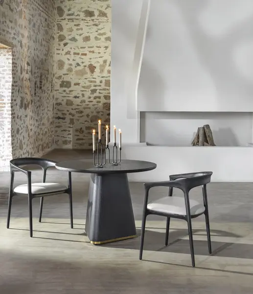 Two Fau Armchairs with black wooden frames and white seats arranged around a central dining table in a rustic room.
