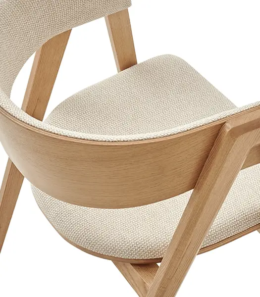 High-angle perspective of the Gala W Armchair, emphasizing the curved backrest design and pale beige fabric upholstery.