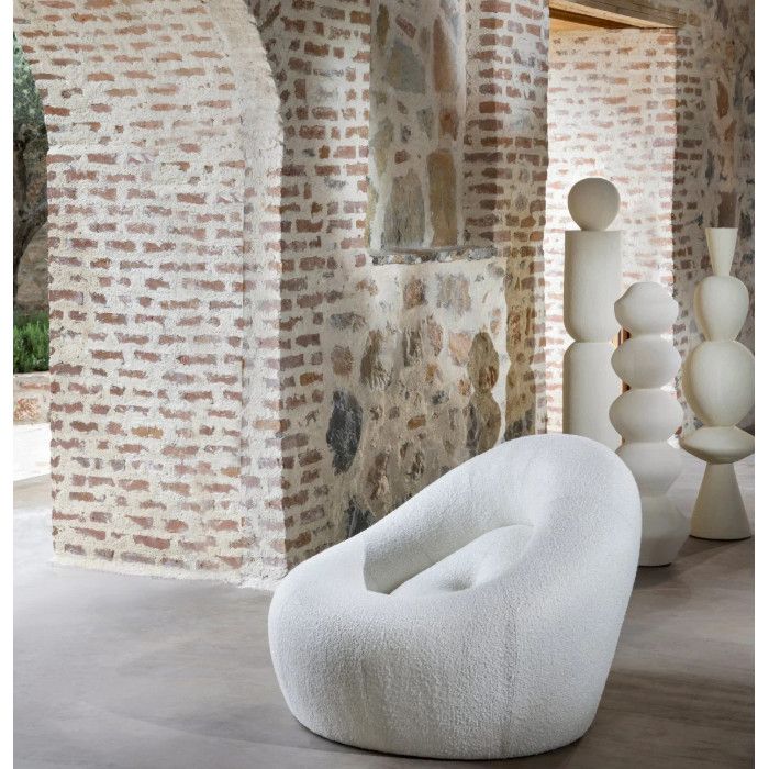 Modern Loop Sofa in white textured fabric, featuring a low-profile curved silhouette shown against a rustic brick arch.