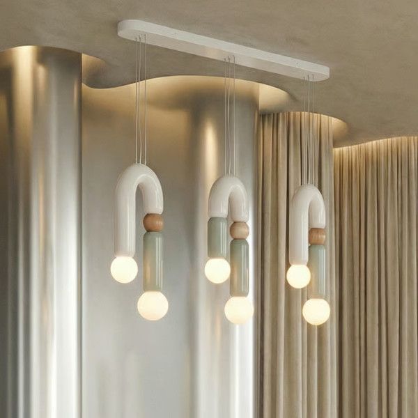 Play III pendant light cluster showing three multi-colored U-shaped frames with wood detailing and spherical bulbs.