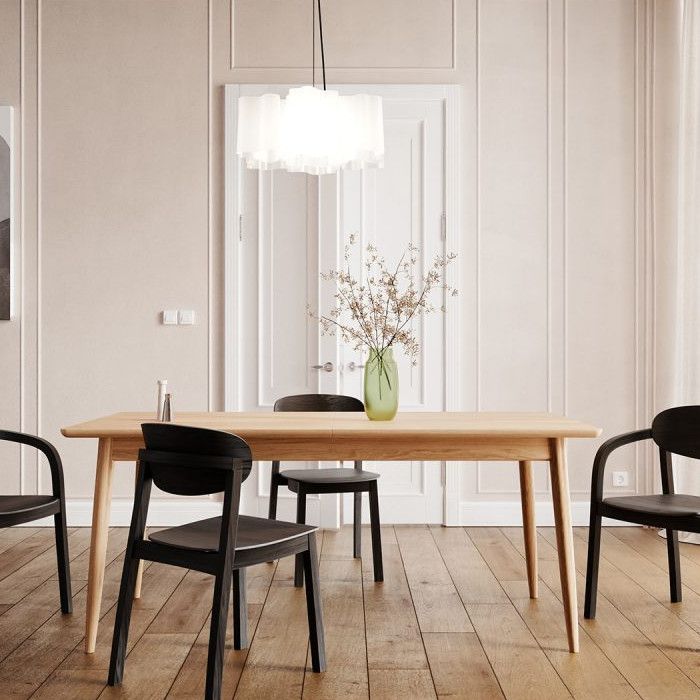Toscano rectangle dining table with a natural wood finish, shown in a bright interior paired with modern black chairs.