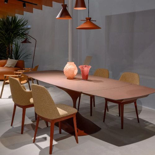 Wide-angle view of the Leo Extendable Dining Table featuring a warm-toned veneer and distinctive curved metal pedestal.