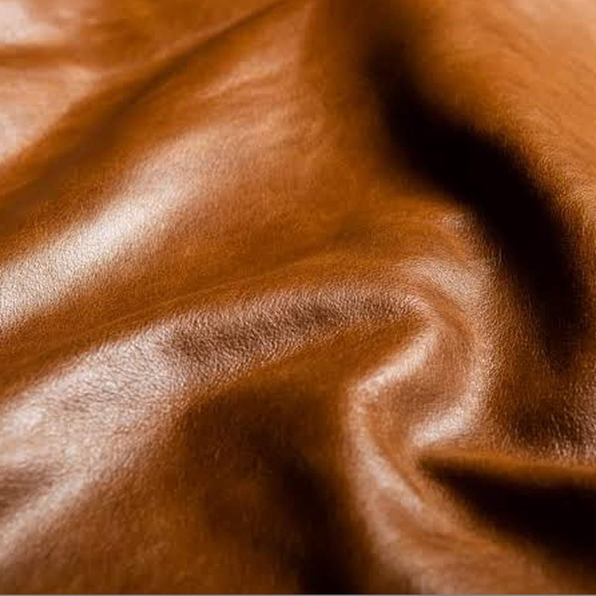 real-leather Rich cognac-colored leather displays natural grain and deep, fluid folds catching highlight and shadow.