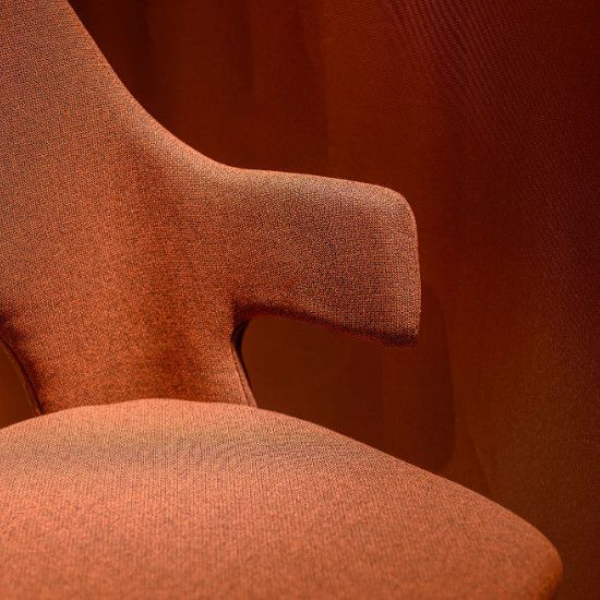 Close-up of the Relay Open Back Armchair in textured terracotta upholstery, highlighting the curved armrest profile.